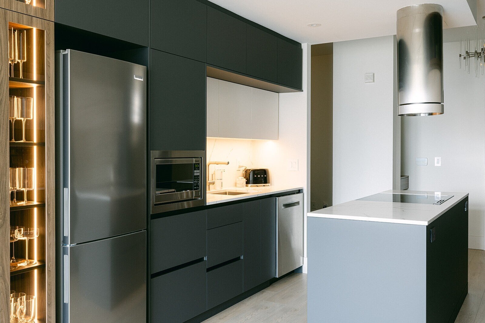 Modern condo kitchen renovation with matte black cabinetry, stainless steel appliances, and a white quartz island by Golden Bee Homes.