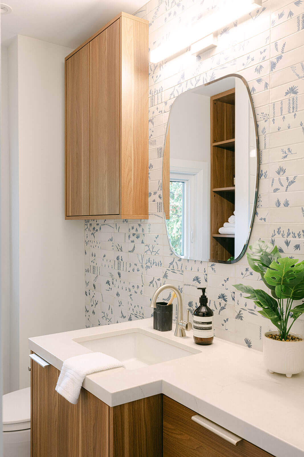 A stylish bathroom featuring a sink, mirror, and plant, showcasing renovation materials by Golden Bee Homes.