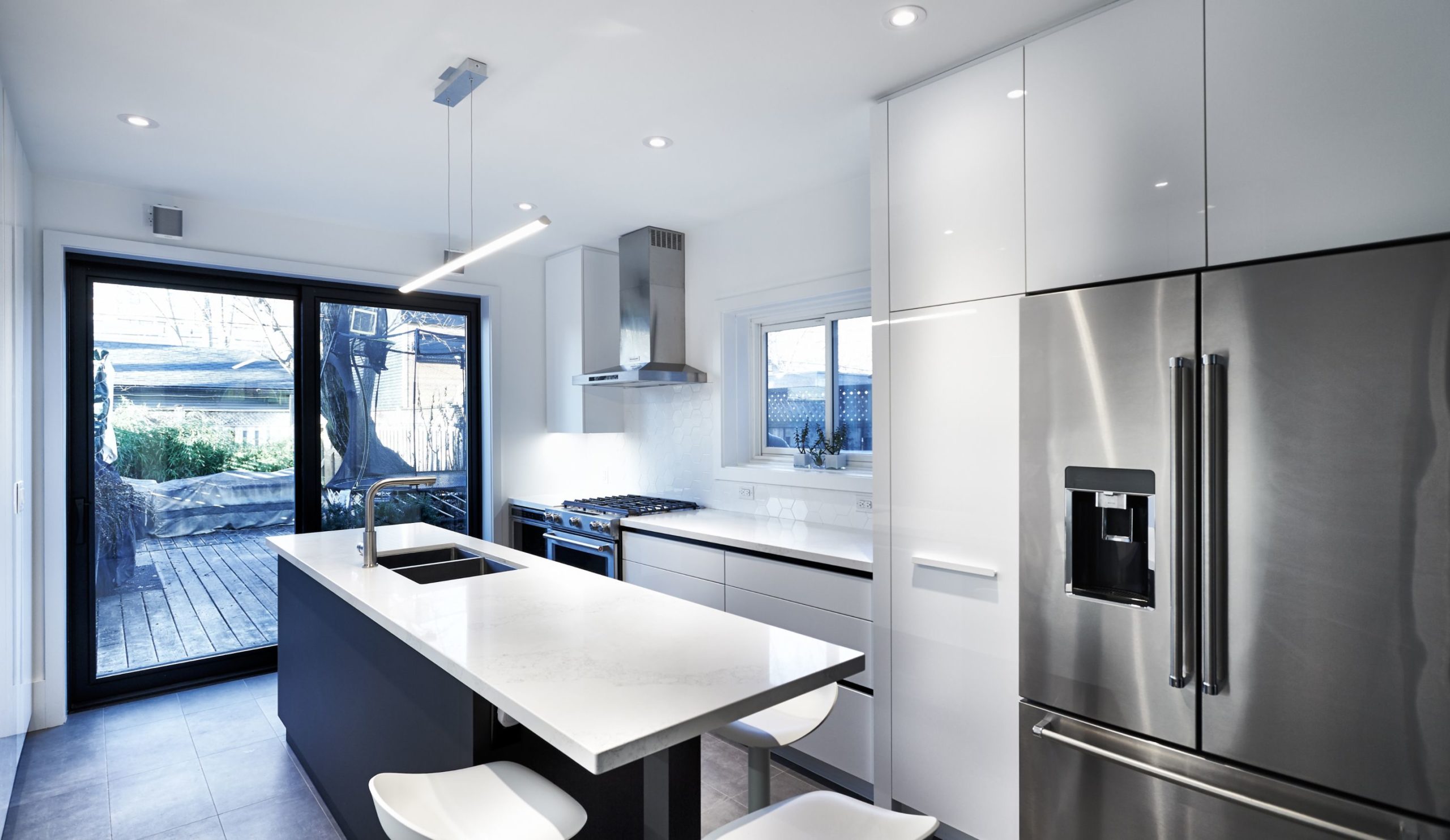 A modern kitchen featuring stainless steel appliances and white countertops, showcasing the design by Golden Bee Homes.