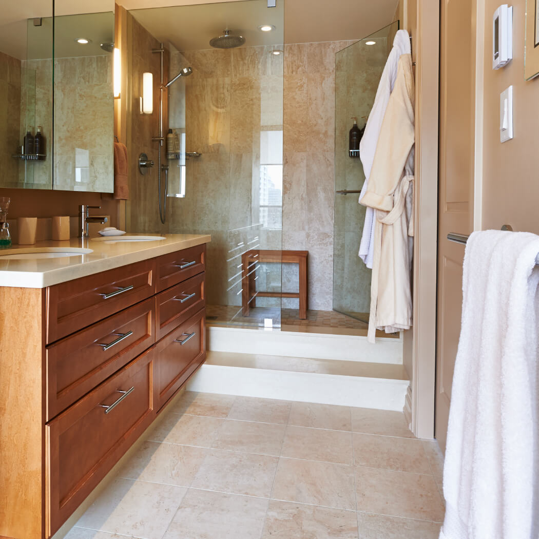 Renovated bathroom with double vanity and wood-grain cabinets.