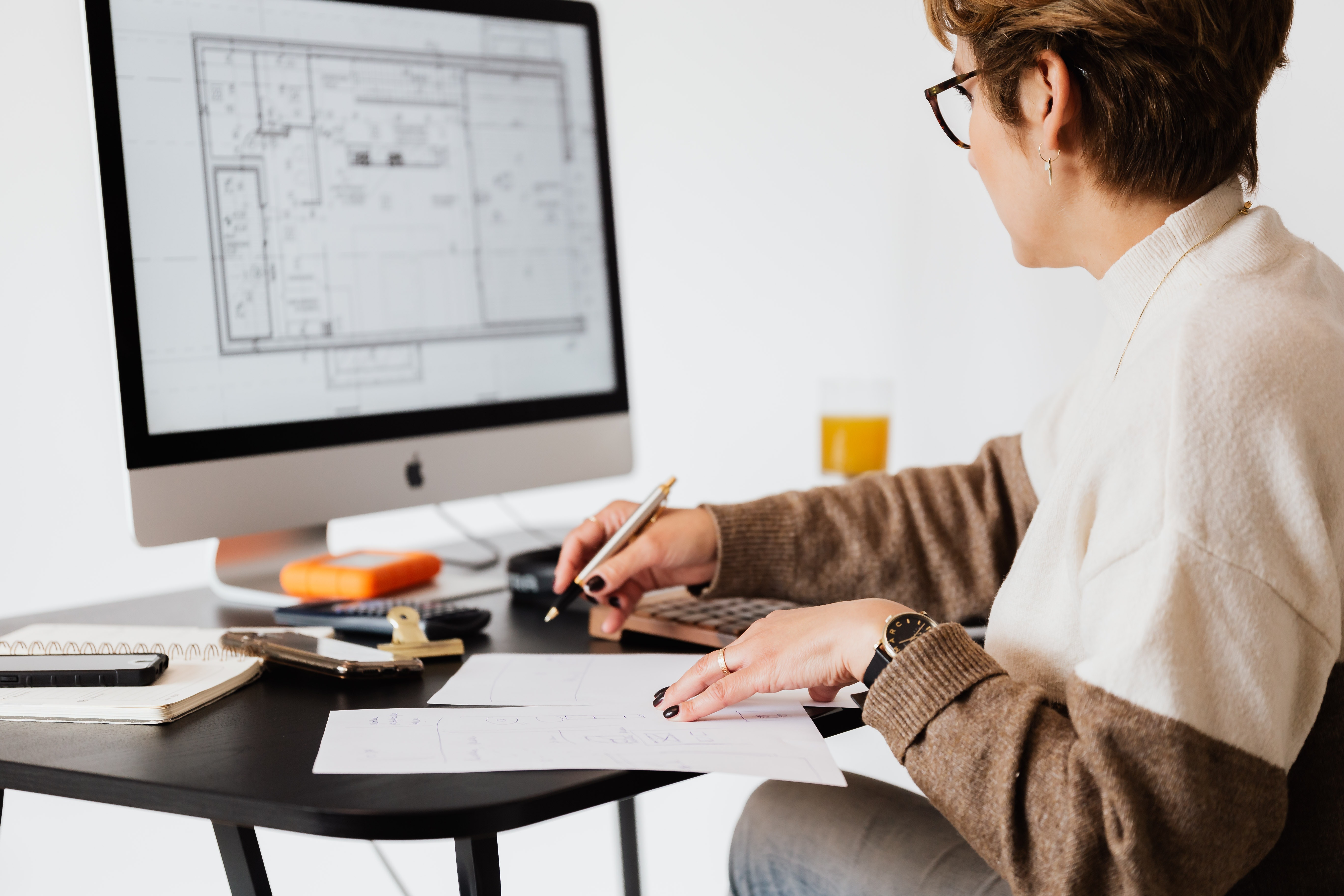 Woman adjusting blue print of custom home design on her computer.